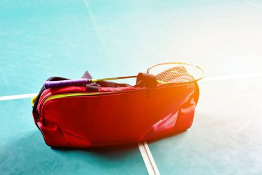 Badminton raketleri kırmızı çanta ve badminton için diğer ekipmanlar kapalı badminton kortunun yeşil zemininde oynuyor, hafif düzenlenmiş, yumuşak ve seçici odaklı.