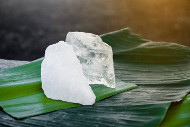 Şeffaf kristal alyum taşı veya muz yaprağı üzerinde potasyum alyum, kimyasal bileşik. Güzellik ve spa tedavisi kavramı ve koltukaltı altında vücut kokusuna deodorant muamelesi yapmak ve suyu berrak kılmak.