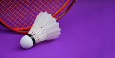 Beyaz kremalı badminton mekikleri ve raketleri mor zeminde, badminton kortunda fotokopi alanı, badminton spor aşığı ve dayanıklılık konsepti..
