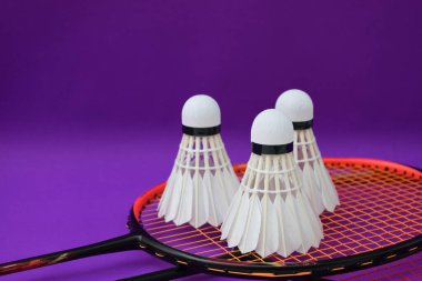 Beyaz kremalı badminton mekikleri ve raketleri mor zeminde, badminton kortunda fotokopi alanı, badminton spor aşığı ve dayanıklılık konsepti..
