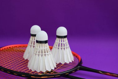 Beyaz kremalı badminton mekikleri ve raketleri mor zeminde, badminton kortunda fotokopi alanı, badminton spor aşığı ve dayanıklılık konsepti..