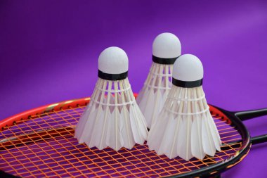 Beyaz kremalı badminton mekikleri ve raketleri mor zeminde, badminton kortunda fotokopi alanı, badminton spor aşığı ve dayanıklılık konsepti..