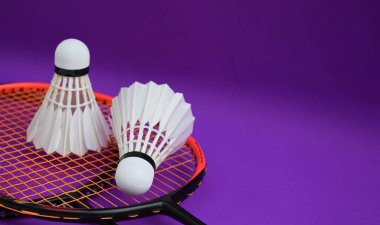 Beyaz kremalı badminton mekikleri ve raketleri mor zeminde, badminton kortunda fotokopi alanı, badminton spor aşığı ve dayanıklılık konsepti..