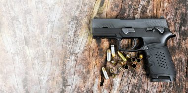 9 mm 'lik otomatik tabanca ve mermiler, tahta masadaki mermi kovanları, kopyalama alanı, yumuşak ve seçici odak tabanca.