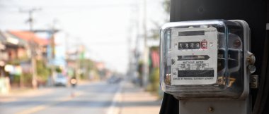 Yol kenarındaki çimento direğine asılan saat göstergesi Asya 'daki her evde elektrik kullanımını izlemek ve ölçmek için..