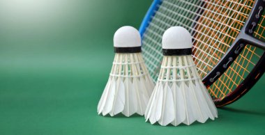 Badminton raketi ve krem beyazı badminton servis aletleri kapalı badminton kortunda yeşil zeminde, badminton raketi ve sicim üzerine seçici odaklanma, kopyalama alanı.