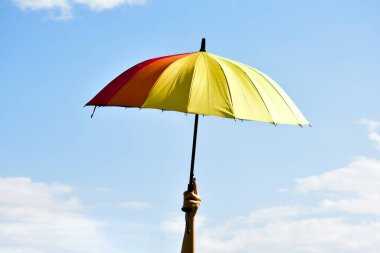 Çok renkli şemsiye, günün öğleden sonra elinde, bulanık arka planda..