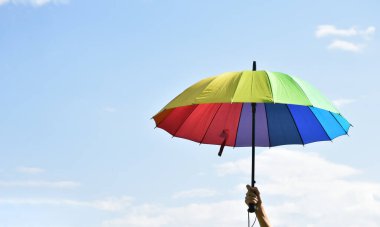 Çok renkli şemsiye, günün öğleden sonra elinde, bulanık arka planda..