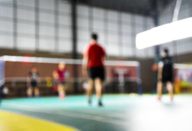 Badminton oyuncularının sahada oynadığı kapalı badminton kortlarının bulanık görüntüsü, dünyanın dört bir yanındaki badminton severler için konsept.