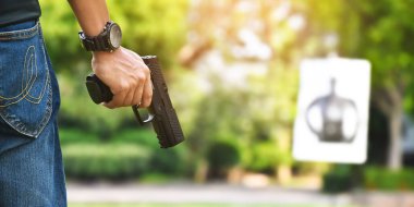 Otomatik siyah 9 mm 'lik tabanca nişancının elinde ve ilerideki hedef tahtasını hedef alıyor. İnsanları koruma, VIP koruyucusu ve gangsterler olmak için eğitme ve uygulama kavramı..