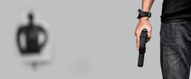 Otomatik 9mm 'lik tabanca, bulanık hedef kâğıdının önünde keskin nişancının sağ elinde, gözaltı ve suç önleme için silah eğitimi kavramı