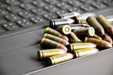 9mm 'lik tabanca mermileri taplet klavyesi ve ekranında, yumuşak ve seçici odak, veritabanını aramak ve depolamak için akıllı aygıtlar kullanarak kurşun türleri öğrenmek için konsept.