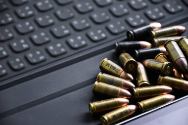 9mm 'lik tabanca mermileri taplet klavyesi ve ekranında, yumuşak ve seçici odak, veritabanını aramak ve depolamak için akıllı aygıtlar kullanarak kurşun türleri öğrenmek için konsept.