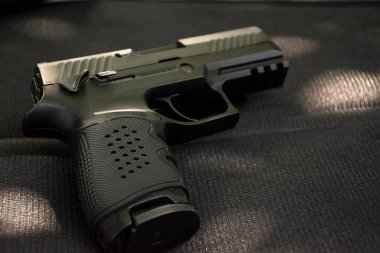 Siyah deri arka planda otomatik 9mm tabanca, yumuşak ve seçici odaklı..