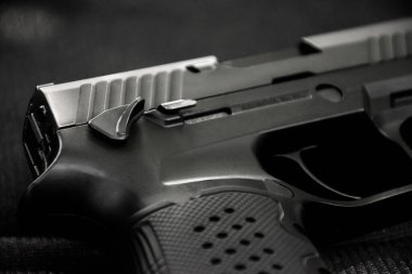 Siyah deri arka planda otomatik 9mm tabanca, yumuşak ve seçici odaklı..