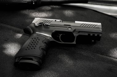 Siyah deri arka planda otomatik 9mm tabanca, yumuşak ve seçici odaklı..