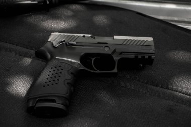 Siyah deri arka planda otomatik 9mm tabanca, yumuşak ve seçici odaklı..