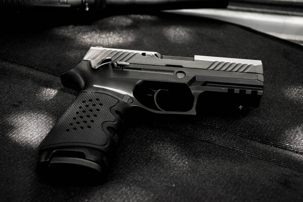 Automatic 9mm pistol gun on black leather background, soft and selective focus.