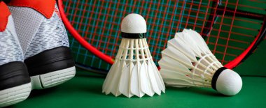 Badminton sahasının yeşil zemininde Badminton spor ekipmanları; mekiklerin horozları, raketler, ayakkabılar, tüm dünyadaki badminton sporu aşığı konsepti üzerine seçici odaklanma.