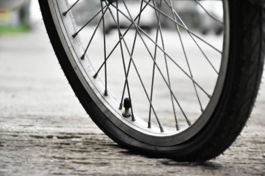 Kaldırıma park etmiş klasik bisikletin ön lastiği, yumuşak ve seçici bir odak noktası..