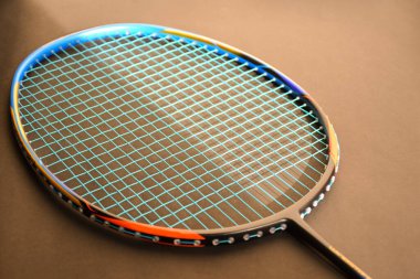 Rackets on orange color floor of the indoor badminton court, soft and selective focus on shuttlecock, concept for badminton sports around the world.