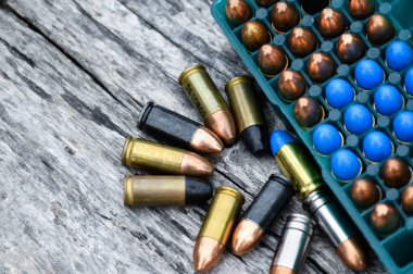Gri ahşap arka planda atış talimi için 9mm 'lik mühimmat veya mermiler, yumuşak ve seçici odaklanma.