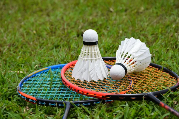 Badminton rakcets and badminton shuttlecocks on grass lawn for outdoor playing afterwork or free times activities in daily life.