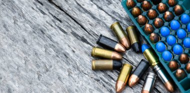 Gri ahşap arka planda atış talimi için 9mm 'lik mühimmat veya mermiler, yumuşak ve seçici odaklanma.