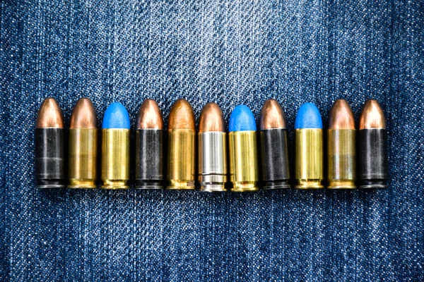 9mm pistol bullets on blue jeans, soft and selective focus, various bullets collecting concept.