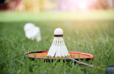 Beyaz kremalı badminton topu ve badminton raketi çimenli arka planda bulanık mekik penisleri açık havada badminton oynamak için konsept, yumuşak ve seçici odaklanma.