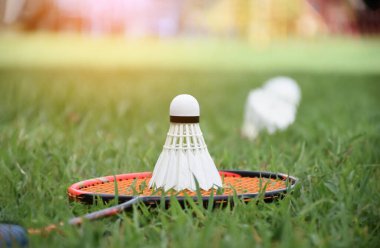 Beyaz kremalı badminton topu ve badminton raketi çimenli arka planda bulanık mekik penisleri açık havada badminton oynamak için konsept, yumuşak ve seçici odaklanma.