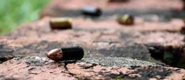 Tuğla zeminde 9mm 'lik tabanca mermileri ve mermi kovanları, yumuşak ve seçici odaklanma, olay yerindeki bir cinayet davasında anahtar bir kanıtı aramak için kavram.