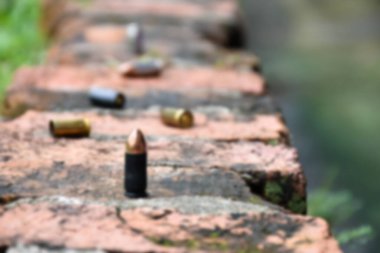 Tuğla zemindeki 9 mm 'lik tabanca mermileri ve mermi kovanlarının bulanık görüntüsü. Olay yerindeki bir cinayet davasında önemli bir kanıtı aramak için kullanılan kavram..