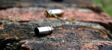 9mm pistol bullets and bullet shells on brick floor, soft and selective focus on black bullet shell, concept for searching a key piece of evidence in a murder case at the scene.