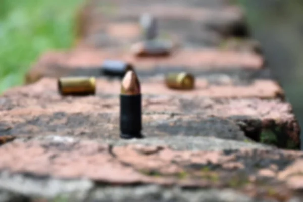 Blurred image of 9mm pistol bullets and bullet shells on brick floor, concept for searching a key piece of evidence in a murder case at the scene.