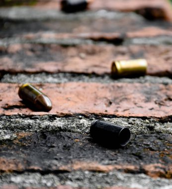 Tuğla zeminde 9mm 'lik tabanca mermileri ve mermi kovanları, yumuşak ve seçici odaklanma, olay yerindeki bir cinayet davasında anahtar bir kanıtı aramak için kavram.