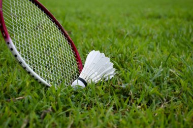 Badminton raketi kullanarak badminton servis horozunu kapmak, raket ve servis horozuna odaklanmak, açık havada badminton oynamak..