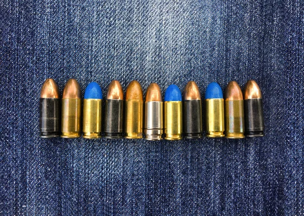 9mm pistol bullets for shooting training and camping on blue jeans, soft and selective focus on bullets, copy space.