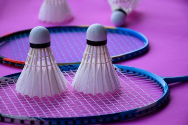 Beyaz kremalı badminton mekikleri, badminton raketleri kapalı badminton kortunun karanlık zemininde, yumuşak ve seçici bir odak noktası, dünyanın dört bir yanındaki badminton sporcuları için konsept.