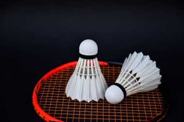Beyaz kremalı badminton mekikleri, badminton raketleri kapalı badminton kortunun karanlık zemininde, yumuşak ve seçici bir odak noktası, dünyanın dört bir yanındaki badminton sporcuları için konsept.