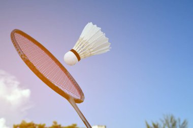 Badminton raketi ve badminton servis aletine karşı bulutlu ve mavi arka plan, açık hava badminton konsepti. rakete seçici odak.