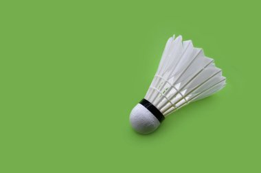 Yeşil arka planda beyaz kremalı badminton servis horozu, günlük hayatta eğlence aktivitesi konsepti.