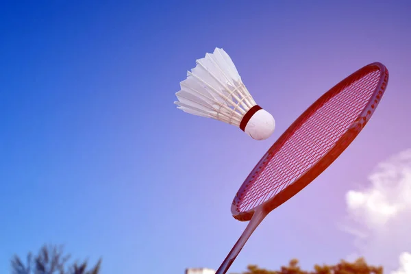 Badminton racket and badminton shuttlecock against cloudy and bluesky background, outdoor badminton playing concept. selective focus on racket.