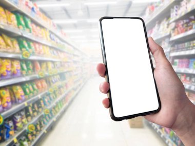 Mockup Mobile phone holding in hand with blurred supermarket background, concept for using smart devices with online shooping apps, online transactions and checking the goods price at home, at work, on application and in daily life.