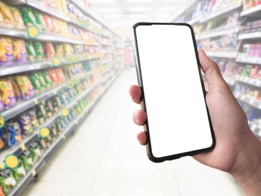 Boş beyaz dokunmatik cep telefonu elinde, bulanık süpermarket arka planı, kontrol etmek, sipariş etmek, bazı malları satın almak ve çevrimiçi işlem yapmak için cep telefonu uygulamasını kullanma kavramı.