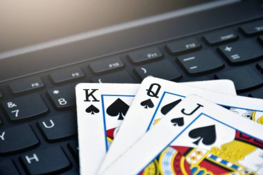 Poker paper cards on blank laptop keyboard, soft and selective focus, concept for playing cards online with other people at home and recreational activity.