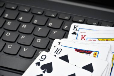 Poker paper cards on blank laptop keyboard, soft and selective focus, concept for playing cards online with other people at home and recreational activity.