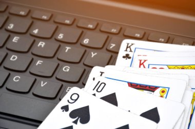 Poker paper cards on blank laptop keyboard, soft and selective focus, concept for playing cards online with other people at home and recreational activity.