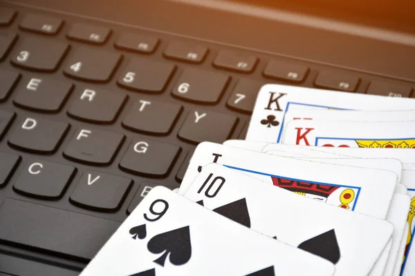 Poker paper cards on blank laptop keyboard, soft and selective focus, concept for playing cards online with other people at home and recreational activity.