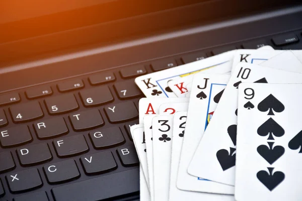 Poker paper cards on blank laptop keyboard, soft and selective focus, concept for playing cards online with other people at home and recreational activity.